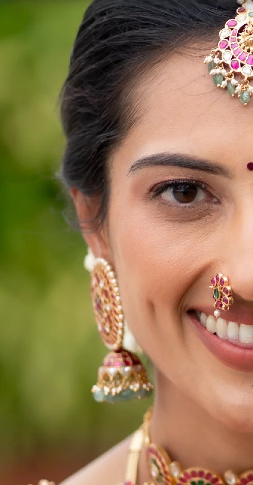 Close-up of the same portrait: her eye, the stones of her jhumka earring and nose ring, and her smile